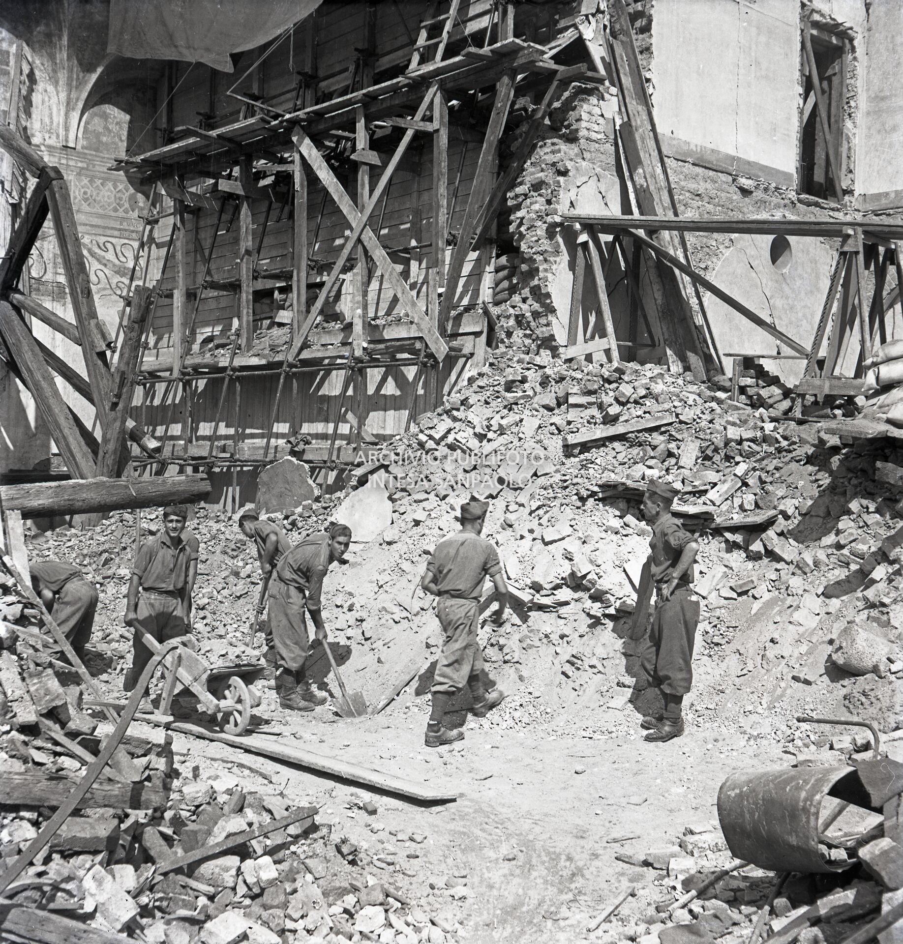 Lavori di rimozione delle macerie della basilica di Santa Maria delle Grazie a Milano dopo i bombardamenti; sullo sfondo sono visibili le impalcature di legno, i sacchi di sabbia, e i rinforzi metallici, su entrambi lati della parete settentrionale del refettorio del convento annesso alla basilica, messi a protezione del Cenacolo vinciano che lo salvaguardarono