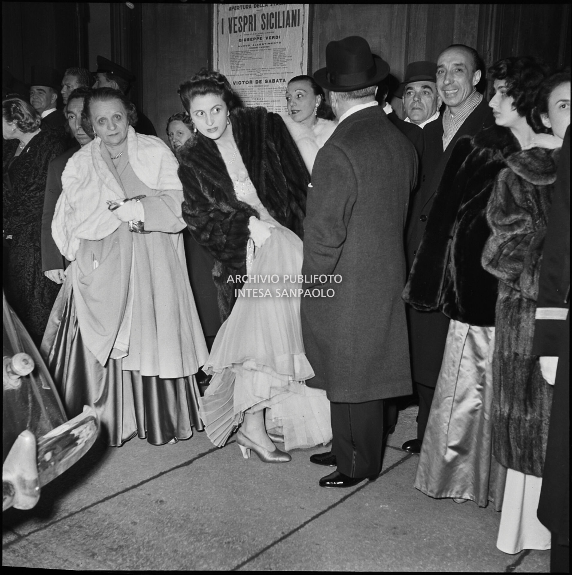 Spettatori all'esterno del Teatro alla Scala, nella galleria delle carrozze, la sera dell'inaugurazione della stagione lirica 1951-1952 con l'opera "I vespri siciliani" di Giuseppe Verdi, diretta da Victor de Sabata, con la regia di Herbert Graf